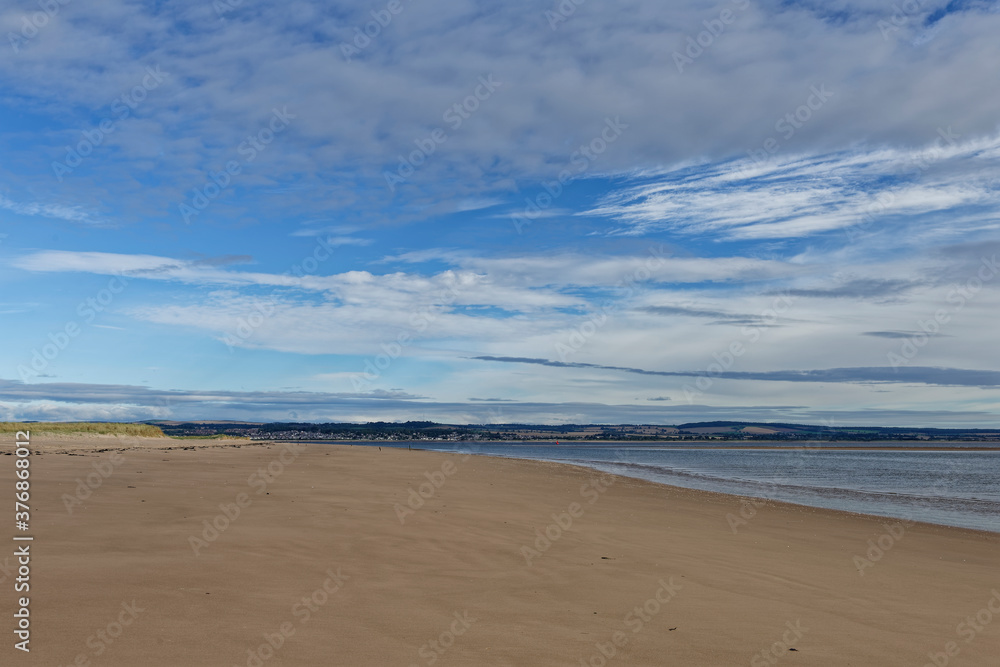 The wide sandy deserted beach of Tentsmuir Point on the southern edge of the Tay Estuary, with gentle waves breaking on the sand.