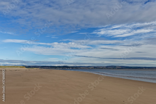The wide sandy deserted beach of Tentsmuir Point on the southern edge of the Tay Estuary, with gentle waves breaking on the sand.