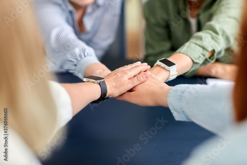 cooperation, corporate and team work concept - close up of business team stacking hands at office