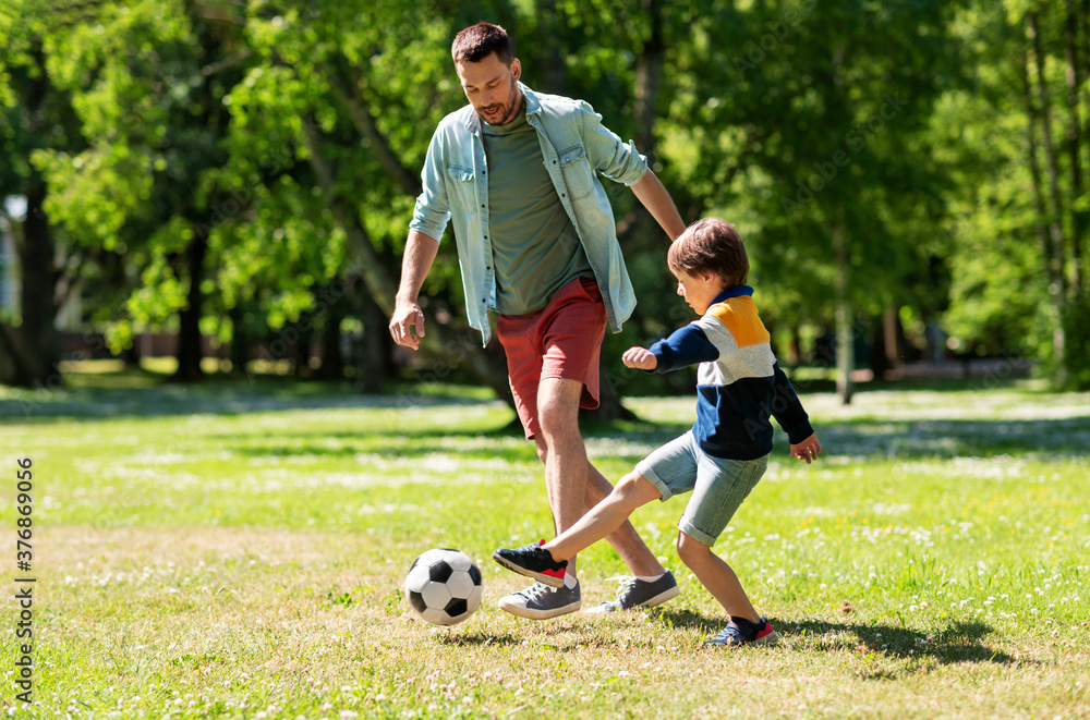 family, fatherhood and people concept - happy father and little son with ball playing soccer at summer park - obrazy, fototapety, plakaty 