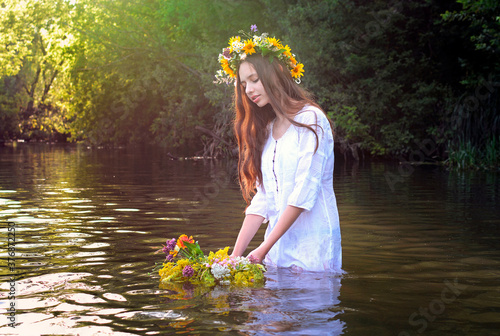 Konstfotografi A young slim girl European appearance in a white shirt stands in the river and h