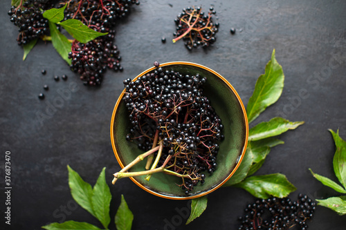 Raw ripe elderberry in a bowl standing on a dark table photo