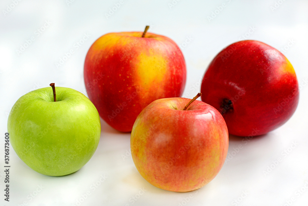 Three red and one green apple on a white background, close-up Three red and one green apple on a white background, close-up