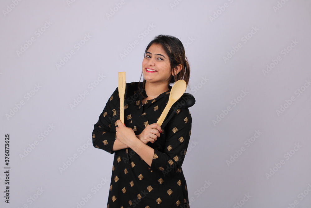 Beautiful Indian girl or woman or home maker holding serving spoon or kitchen ware in hand. Beautiful Indian girl or woman or home maker holding serving spoon or kitchen ware in hand.