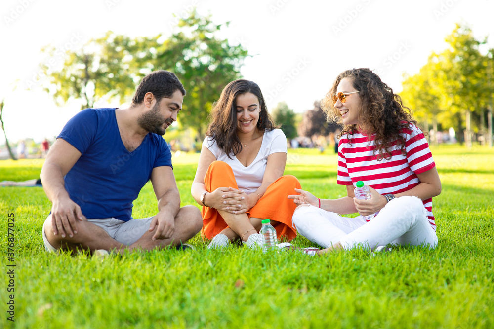 Three friends sitting on the grass in the park
