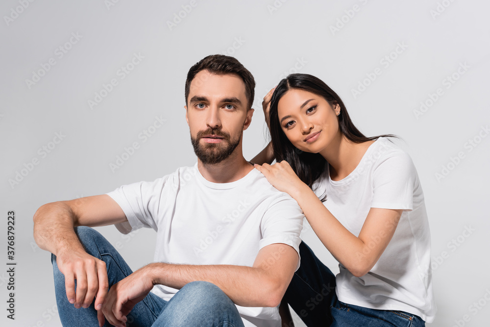 young asian woman looking at camera while sitting near boyfriend isolated on white young asian woman looking at camera while sitting near boyfriend isolated on white