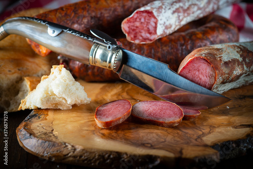 Spanish sausage slices with bread and a folding knife