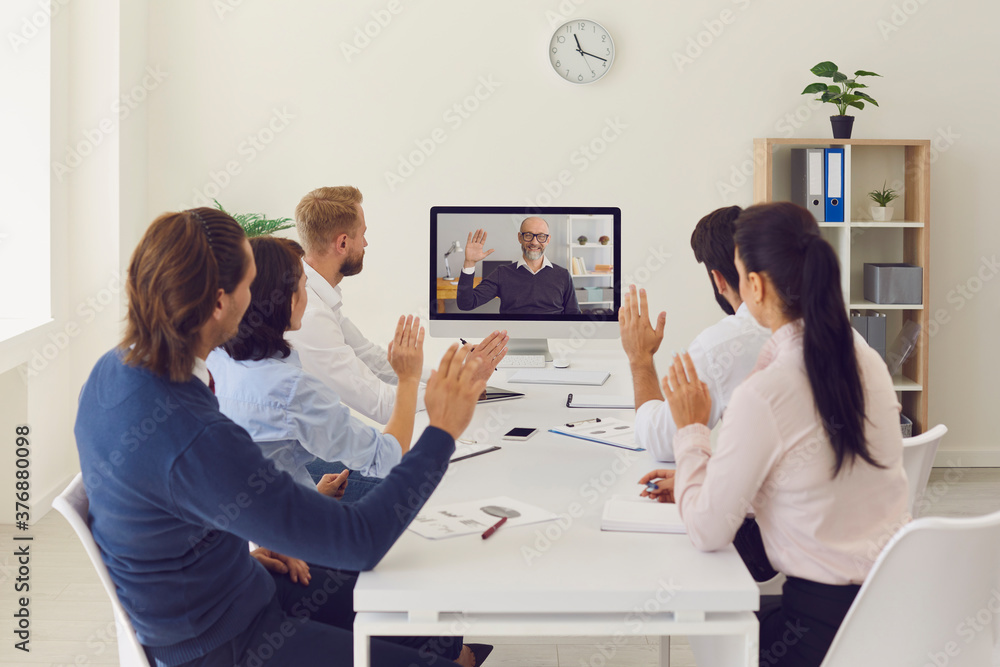 Company workers sitting in office having online meeting with their CEO using desktop computer - obrazy, fototapety, plakaty 