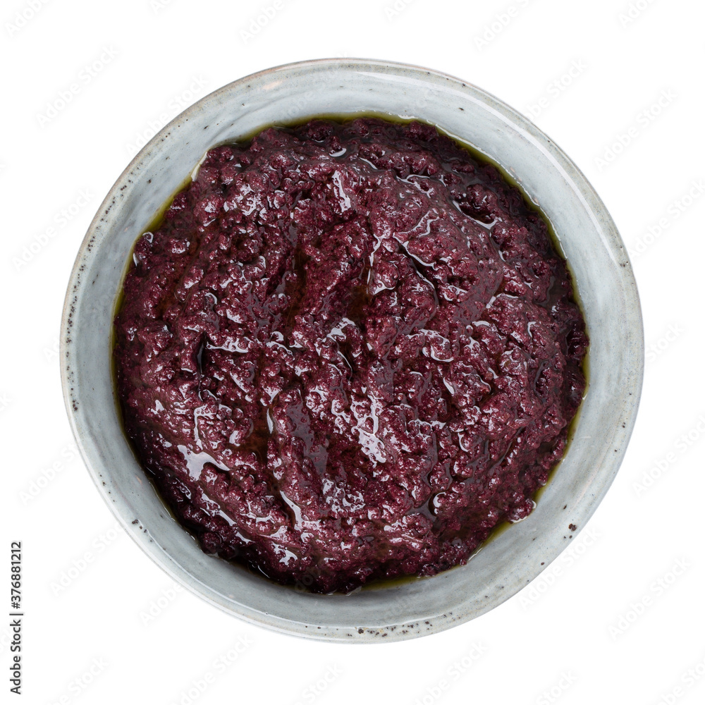Tapenade olive paste made from black olives. Spreadable black olive cream in bowl isolated on