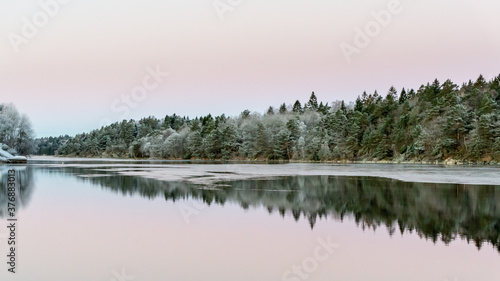 Winter landscape, calm water, reflections. Beautiful silence morning at sunrise, dawn in early winter. Pink colored sky as background, place for text, copy space.