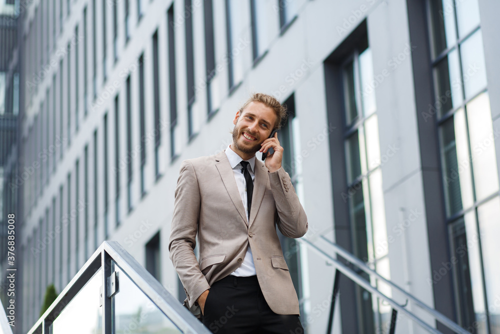 Portrait of a successful young businessman. A curly-haired man in a white shirt with a telephone against the background of a modern business center. Portrait of a successful young businessman. A curly-haired man in a white shirt with a telephone against the background of a modern business center.