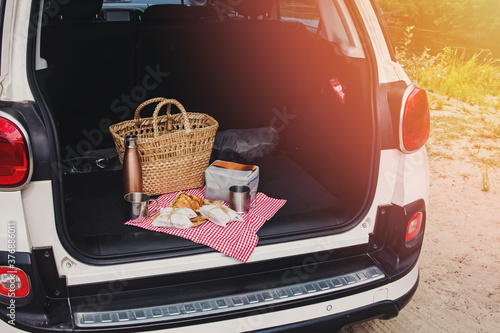 Foto Picnic Package and Basket with Croissant and Sandwiches Lies on the in the trunk
