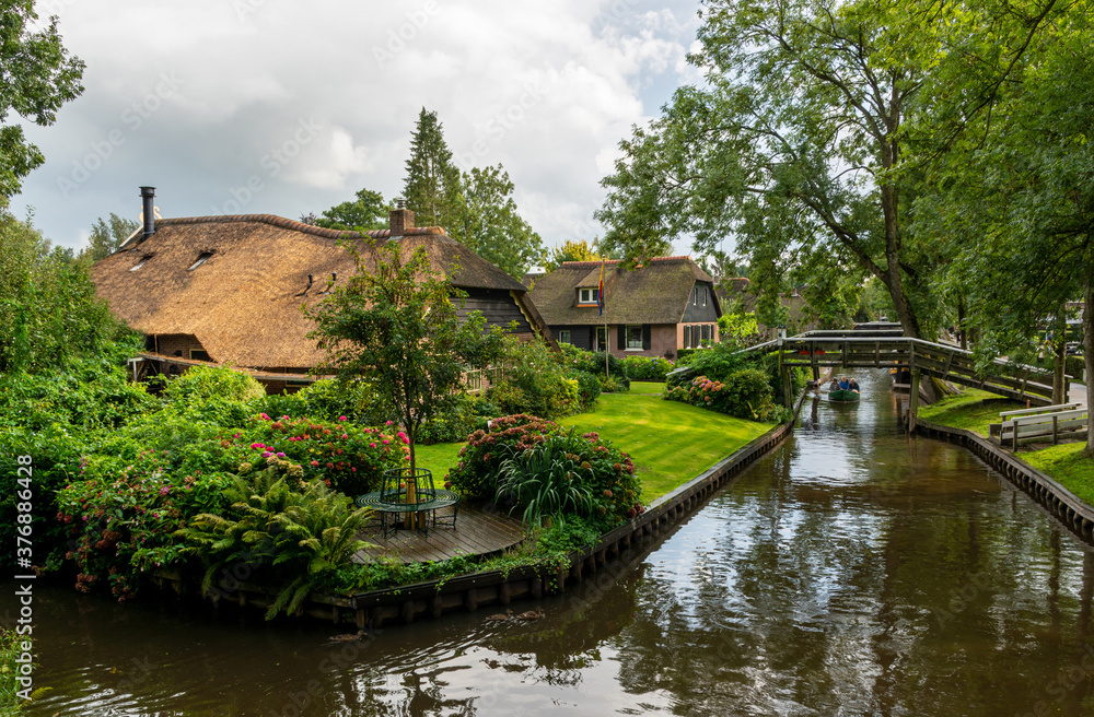 Obraz premium Giethoorn, The Netherlands - August 28, 2020: View over thatched roof houses and a boat on the canal