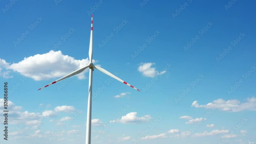 Wind turbine spinning around at the blue cloudy sky background. Wind turbine spinning around at the blue cloudy sky background.