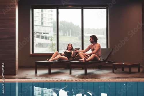Couple enjoying their spa center vacation, relaxing by the swimming pool