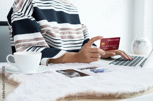 The businesswoman's hand is holding a credit card and using a smartphone for online shopping and internet payment in the office