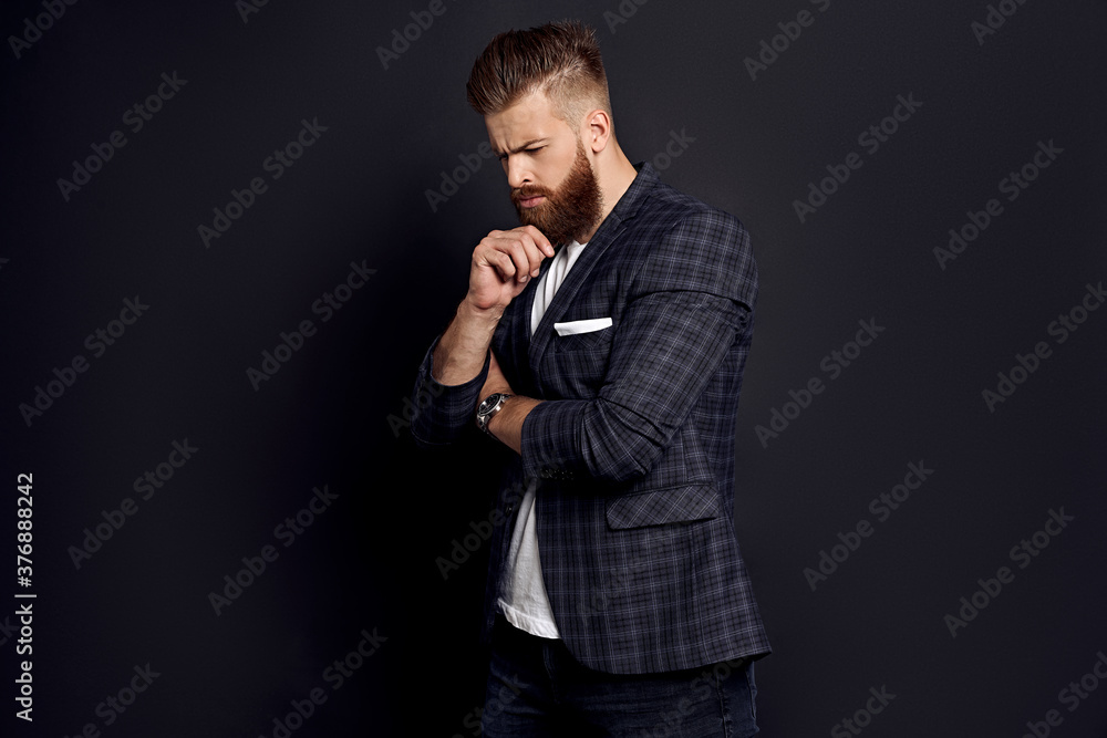 Thinking about something. Upset man with long hair and beard standing against grey background Thinking about something. Upset man with long hair and beard standing against grey background