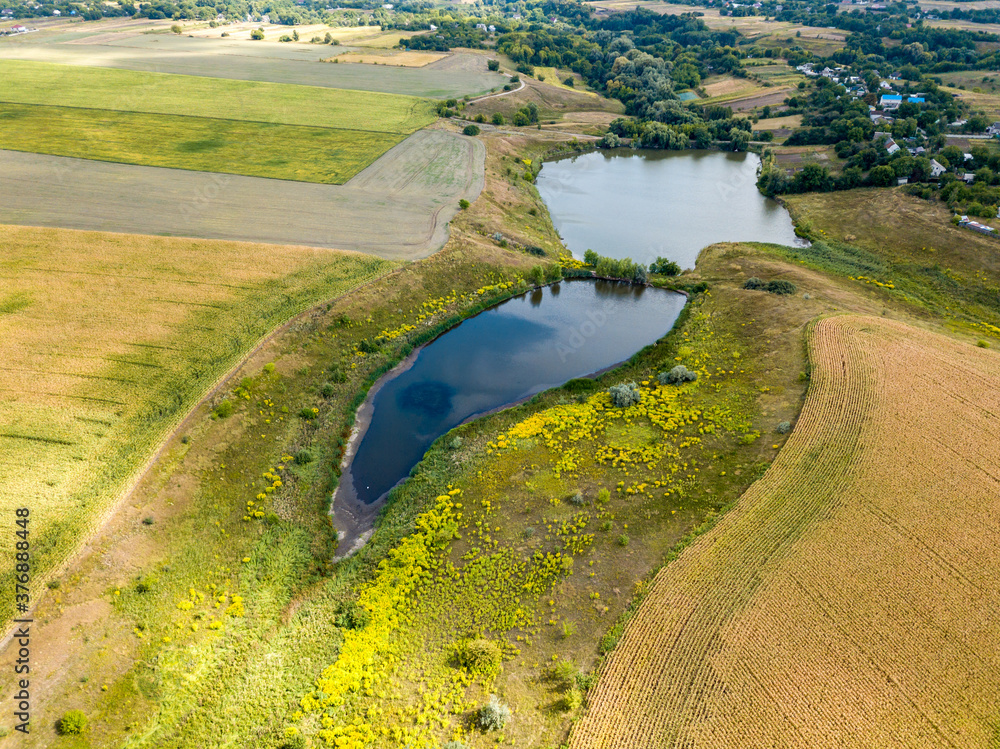 Fototapeta premium Aerial drone view. Country lake among agricultural fields.