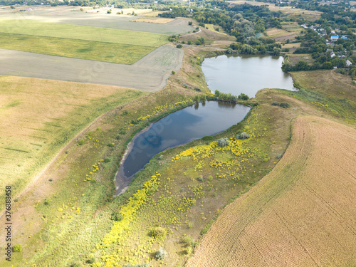 Aerial drone view. Country lake among agricultural fields.