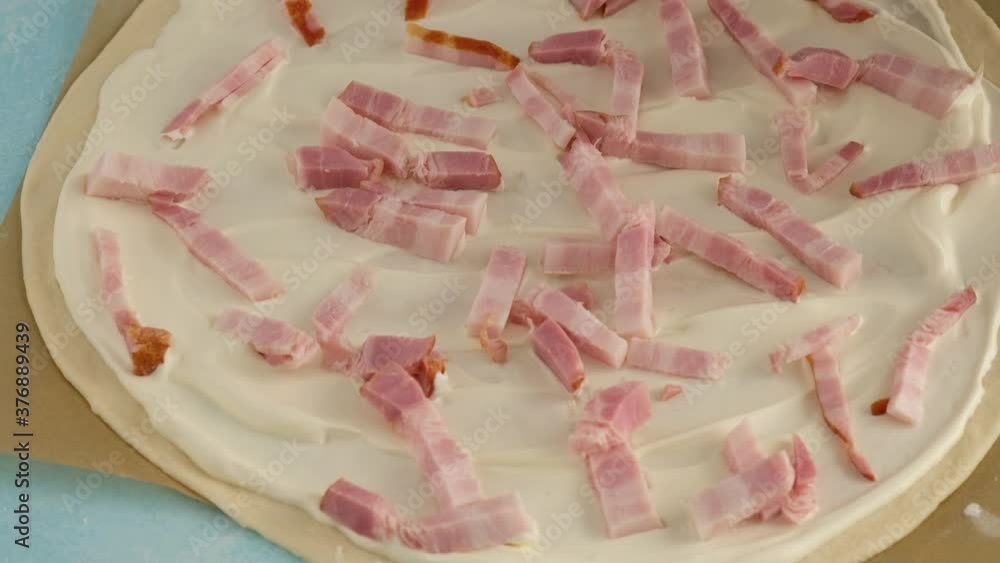 A woman prepares a pie with bacon, onions and sour cream. Flammkuchen pie. A woman prepares a pie with bacon, onions and sour cream. Flammkuchen pie.