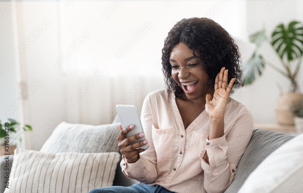 Joyful African Woman Having Video Call With Friends Via Smartphone At Home