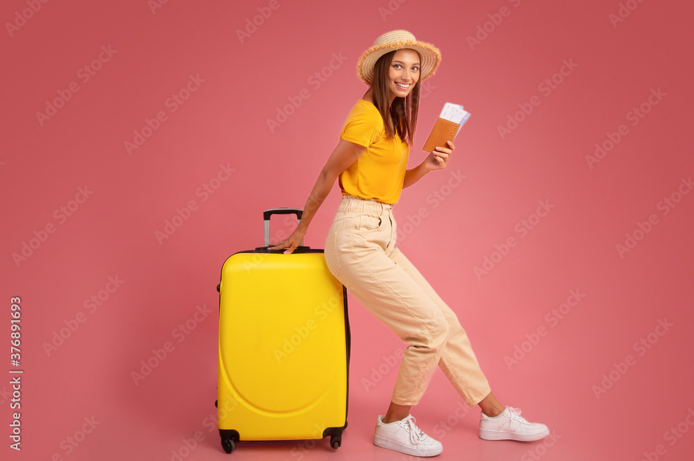 Smiling young woman in summer clothes leaning on luggage Smiling young woman in summer clothes leaning on luggage