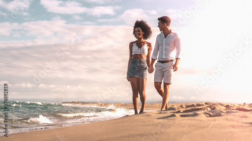 Multiethnic couple walking on the beach on the seashore in the evening. Romantic concept.