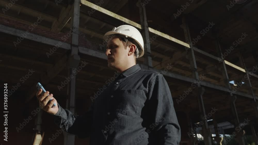 worker, foreman, builder, engineer, architect in a dark shirt, white helmet, at the facility, at the construction site, communicates phone video communication, shows project, negotiates, reports work worker, foreman, builder, engineer, architect in a dark shirt, white helmet, at the facility, at the construction site, communicates phone video communication, shows project, negotiates, reports work