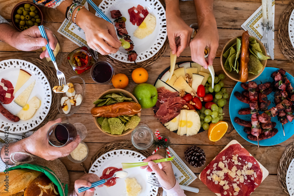 Family friends have fun together in winter eating food on a wooden table - vertical top view and concept of friendship and caucasian people enjoying celebration at home or restaurant