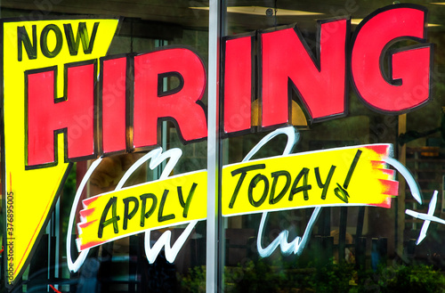 Now hiring apply today sign painted on business window, job, employment, job search, unemployment, economy, market