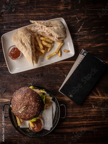 Fresh meat and cheese burger with French fries and black leather menu card. Copy Space, top view.
