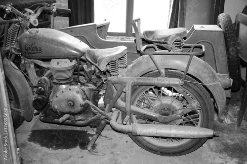Oldtimer Gilera motorbike abandoned in barn in tuscany black and white dust. photo