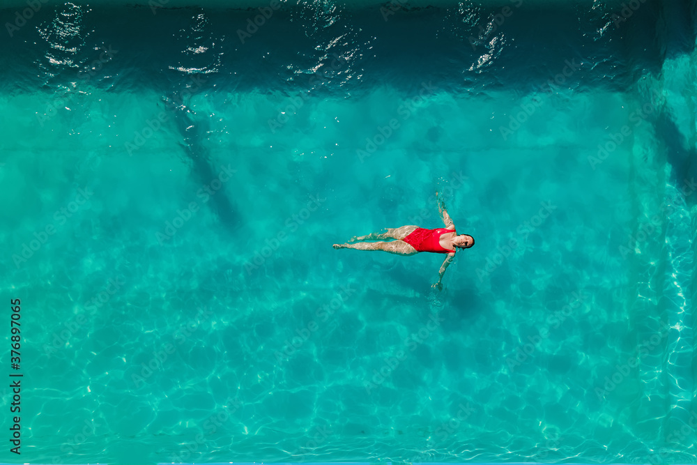 Fototapeta premium Woman in red bikini are swimming in the pool with turquoise water
