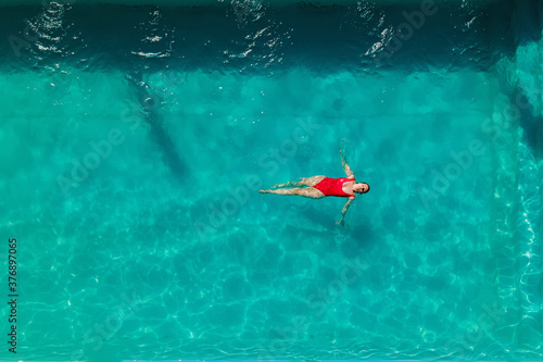 Woman in red bikini are swimming in the pool with turquoise water