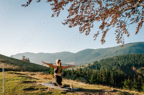 Meditation. Woman balanced  practicing meditation and zen energy yoga in mountains. Girl doing fitness exercise sport outdoors in morning. Healthy lifestyle concept. Sunrise. Back view.