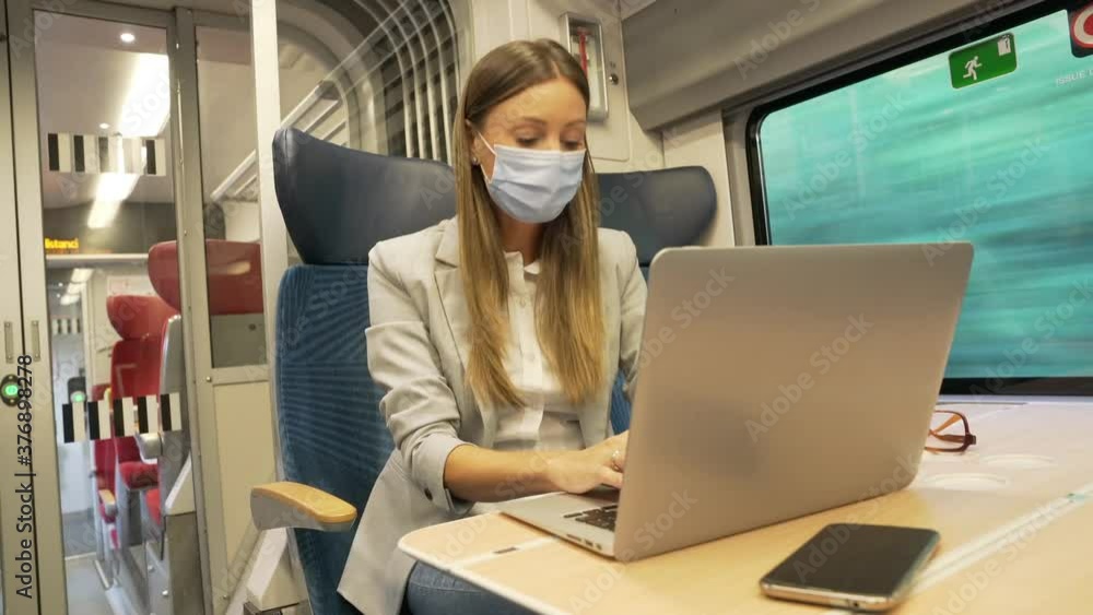 Businesswoman commuting by train, working on digital tablet and wearing face mask Businesswoman commuting by train, working on digital tablet and wearing face mask
