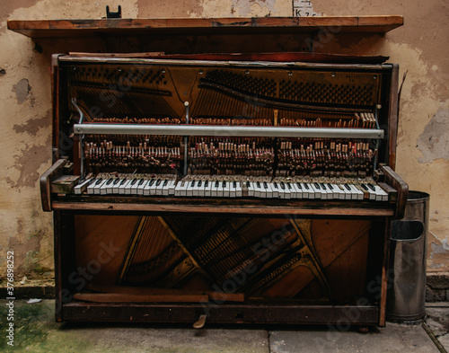 An old and forgotten piano in the city courtyard. A close-up view of a broken keyboard and a hammer mechanism (fenger) of a street piano. The last days of the old piano as an outdoor art object. photo