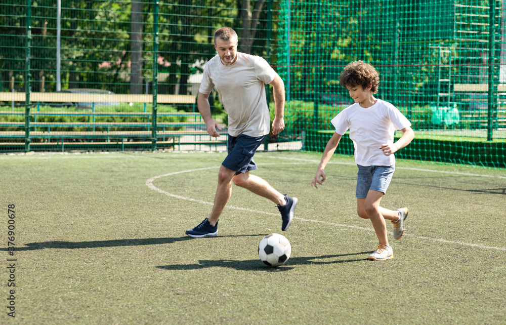 Sportive dad playing soccer with his son