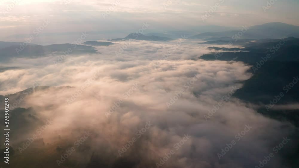 Drone flight over low clouds and morning mists covered mountain slopes at sunrise, the Rhodope Mountains in Bulgaria. Drone flight over low clouds and morning mists covered mountain slopes at sunrise, the Rhodope Mountains in Bulgaria.