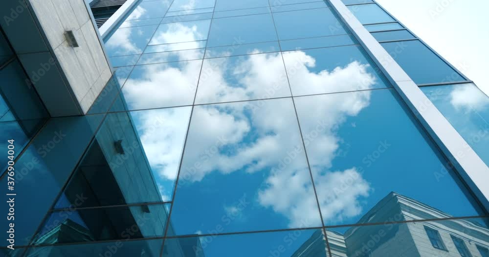Modern futuristic abstract business building high tower blue glass background with reflected white skies and clouds on wall and clear window of architectural construction mirrored urban design pattern Modern futuristic abstract business building high tower blue glass background with reflected white skies and clouds on wall and clear window of architectural construction mirrored urban design pattern