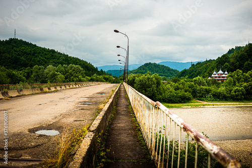 Old broken road across the river in the mountains photo