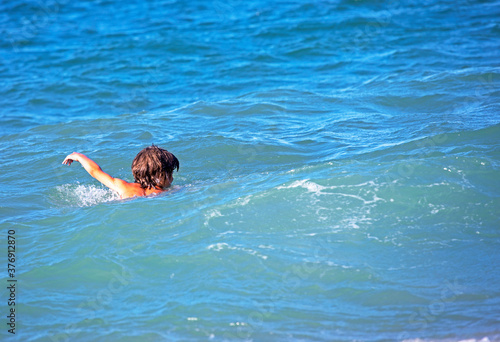 happy boy with his back swims in the sea, horizontal format