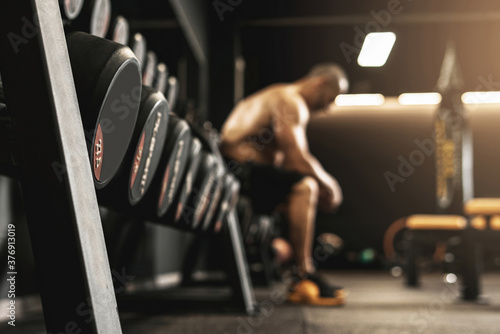 Dumbbells with free space and blurred bodybuilder on background photo
