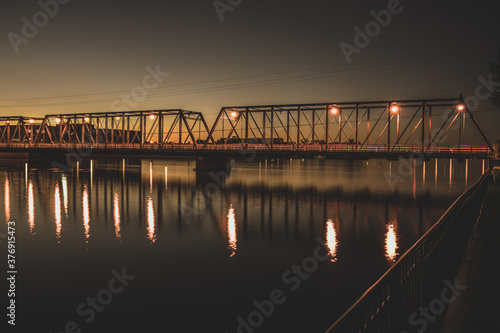 bridge lights reflect on the river at sunset
