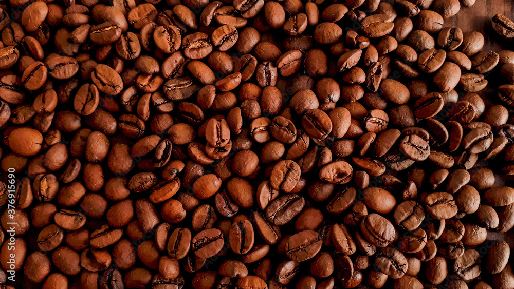 Shaded background of coffee beans scattered on the table.