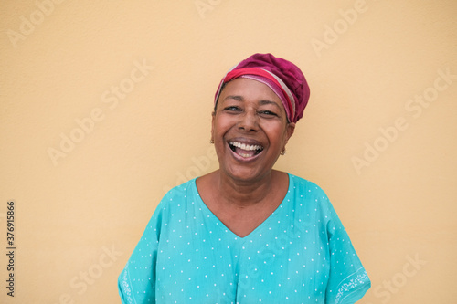 Happy african senior woman laughing and looking in camera - Portrait of real and authentic person wearing traditional dress