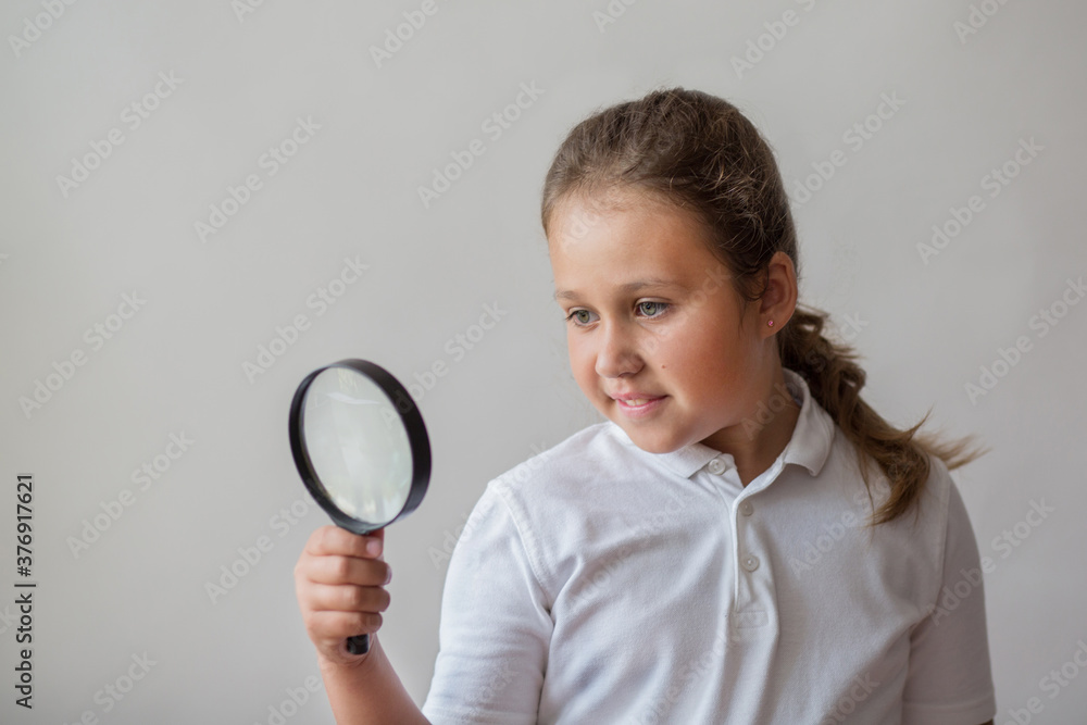Little girl with magnifier on gray background Little girl with magnifier on gray background