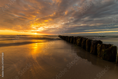 Fototapeta Naklejka Na Ścianę i Meble -  beautiful sunset on the Baltic Sea, waves washing the old wooden breakwaters