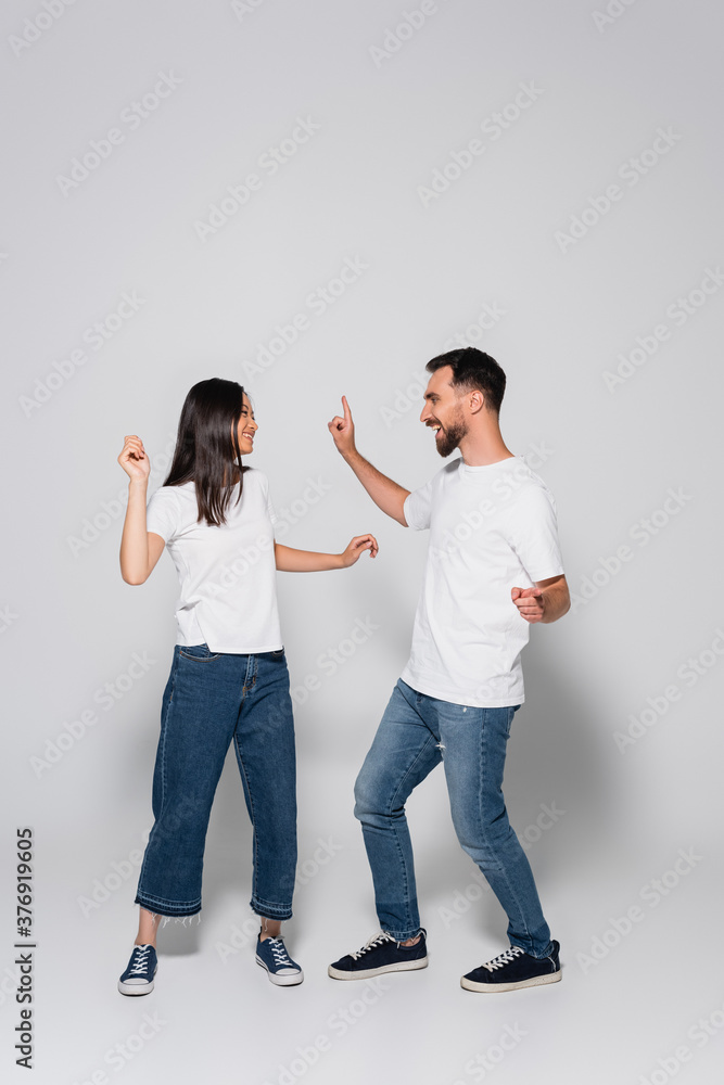 young interracial couple in jeans, white t-shirts and gumshoes dancing while looking at each other on white young interracial couple in jeans, white t-shirts and gumshoes dancing while looking at each other on white