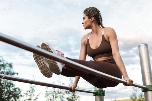 Woman athlete during calisthenics workout on a parallel bars photo